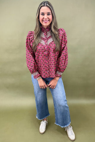 Woman wearing a pink patterned blouse and blue jeans on a green background
