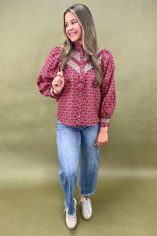 Woman wearing a pink patterned blouse and blue jeans on a green background