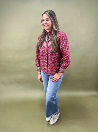 Woman wearing a patterned blouse and jeans on a plain background