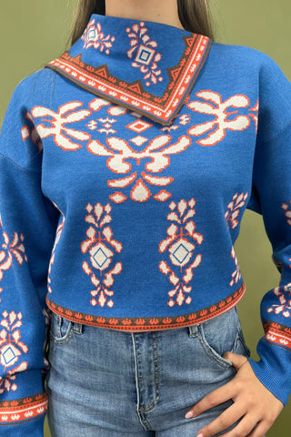 Person wearing a blue sweater with red and white patterns on a green background