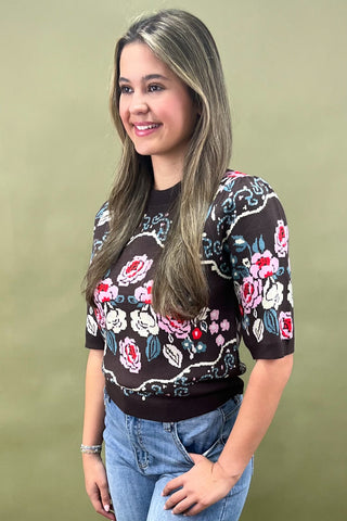 Brown short sleeve knit sweater with colorful floral pattern styled with light wash wide leg jeans and white sneakers