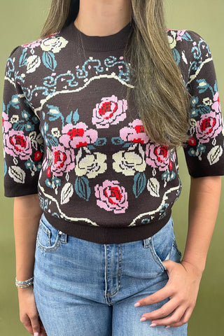 Brown short sleeve knit sweater with colorful floral pattern styled with light wash wide leg jeans and white sneakers