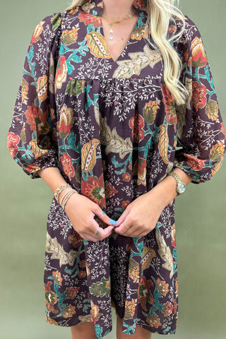 Woman wearing a colorful patterned dress against a green background
