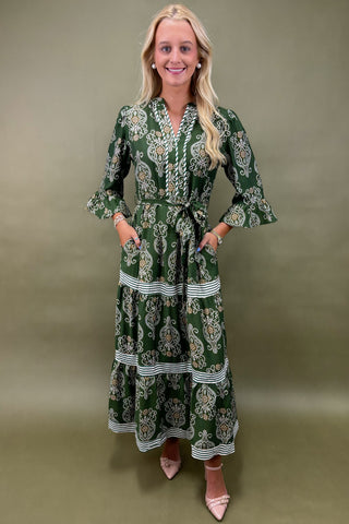 Woman wearing a green patterned dress against a plain background