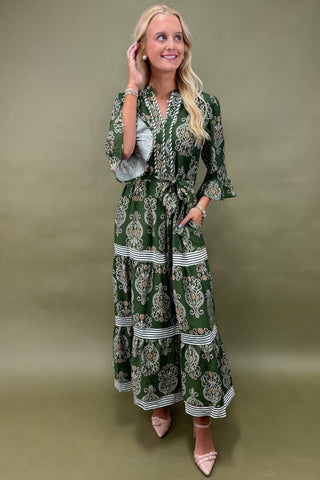 Woman wearing a green patterned dress against an olive green background