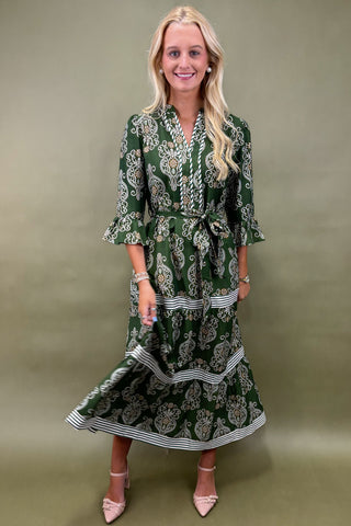 Woman wearing a green patterned dress against a beige background