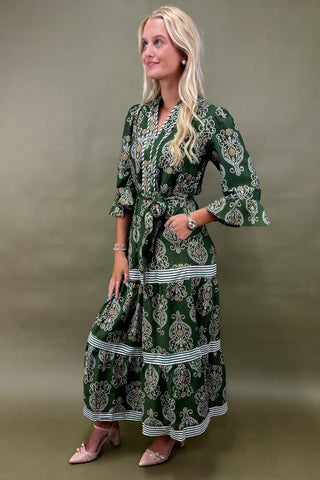 Woman wearing a green patterned dress against a plain background
