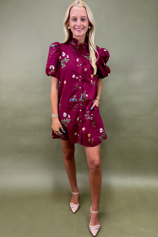 Woman wearing a burgundy floral dress against a green background