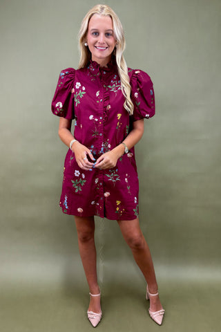 Woman wearing a burgundy floral dress against a green background