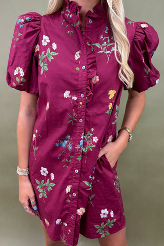 Woman wearing a red top with white trim and light blue jeans against a gray background