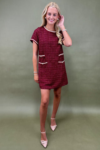 Woman wearing a red checkered dress against a plain background