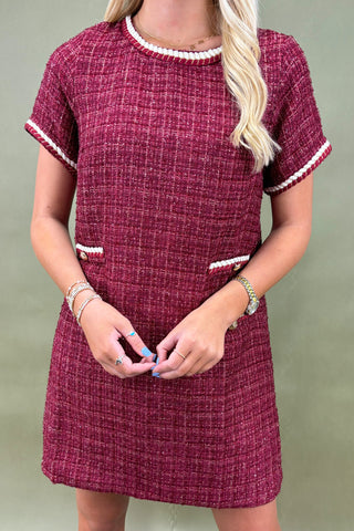 Maroon dress with white trim worn by a person on a plain background