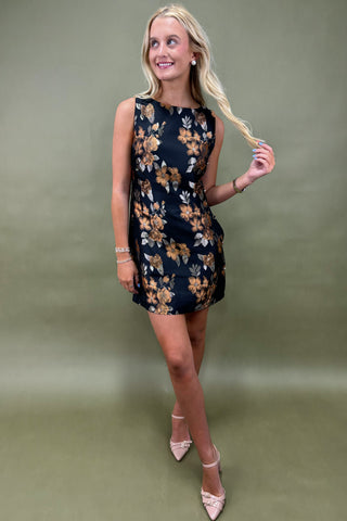 Woman wearing a black floral dress against a green background