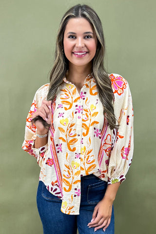 Woman wearing a colorful floral blouse against a green background