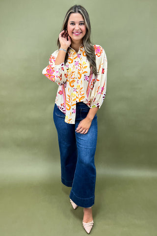 Woman wearing a floral blouse and blue jeans on a green background