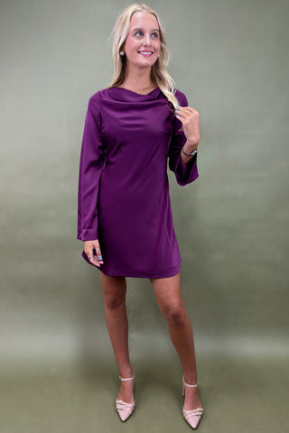 Woman wearing a purple dress against a plain background