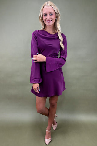 Woman wearing a purple dress against a plain background