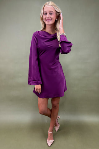 Woman wearing a purple dress against a plain background