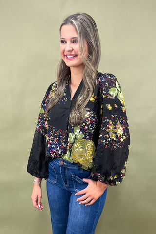 Woman wearing a floral blouse with long sleeves against a beige background