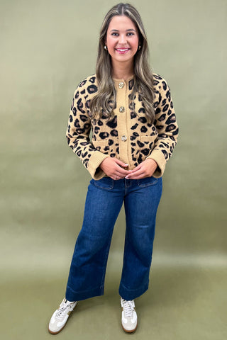 Woman wearing a leopard print jacket and blue jeans against a green background