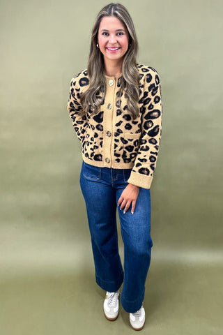 Woman wearing a leopard print jacket and blue jeans on a green background