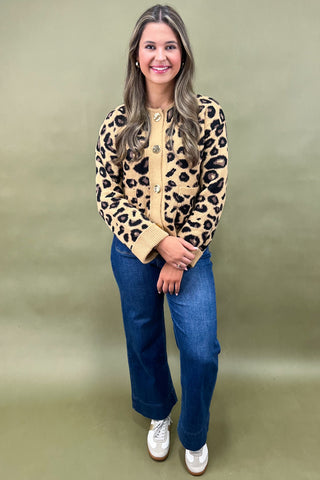 Woman wearing a leopard print cardigan and blue jeans on a green background