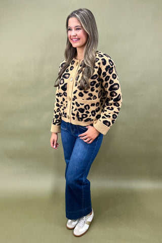 Woman wearing a leopard print jacket and blue jeans on a beige background
