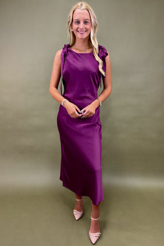 Woman wearing a purple dress against a plain background