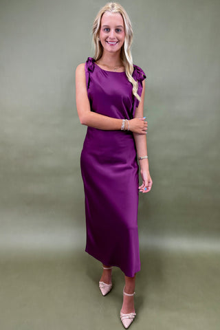 Woman wearing a purple dress against a plain background