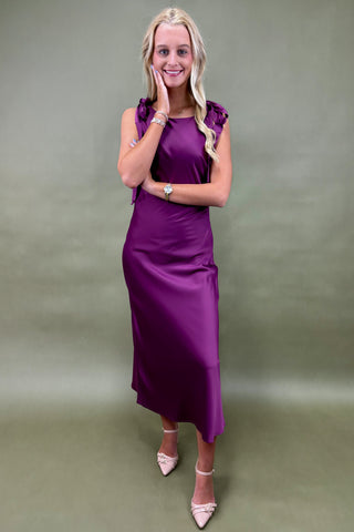 Woman wearing a purple dress against a plain background