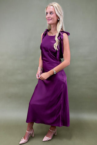 Woman wearing a purple dress against a plain background