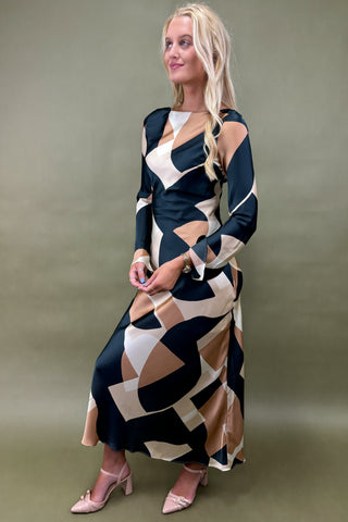 Woman wearing a long, patterned dress against a plain background