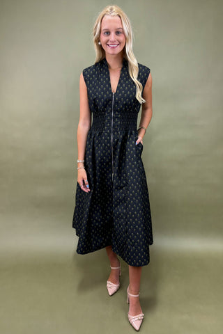 Woman wearing a black patterned dress against a green background