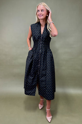 Woman wearing a black patterned dress against a plain background