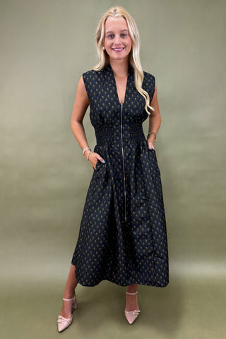 Woman wearing a black sleeveless dress with white polka dots against a green background