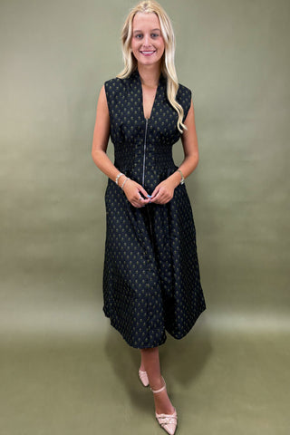 Woman wearing a black sleeveless dress with white polka dots against a green background