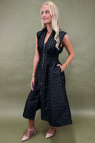 Woman wearing a black patterned dress against a green background