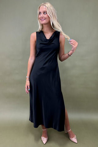 Woman wearing a black sleeveless dress against a green background