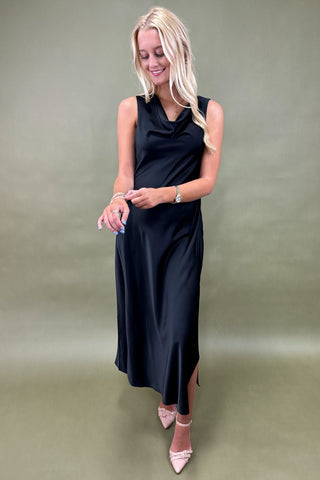 Woman wearing a black sleeveless dress against a plain background