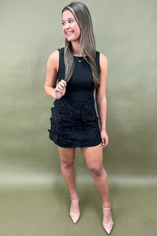 Woman wearing a black dress with floral details on a green background