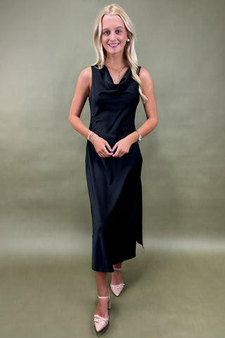 Woman wearing a black sleeveless dress against a green background