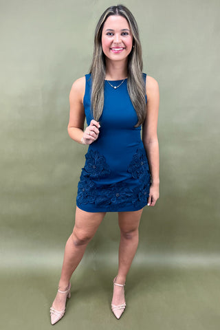 Woman wearing a blue dress with lace details against a green background