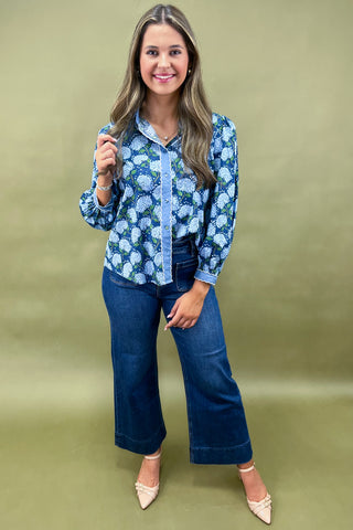 Woman wearing a blue floral blouse and jeans on a green background