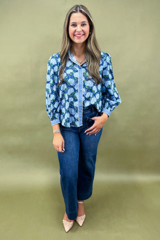 Woman wearing a blue floral blouse and jeans on a green background