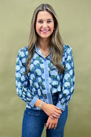 Woman wearing a blue floral blouse against a beige background