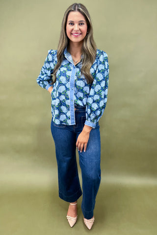 Woman wearing a blue floral blouse and jeans on a beige background
