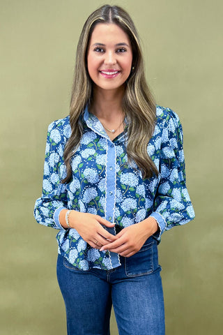 Woman wearing a blue floral blouse and jeans against a green background