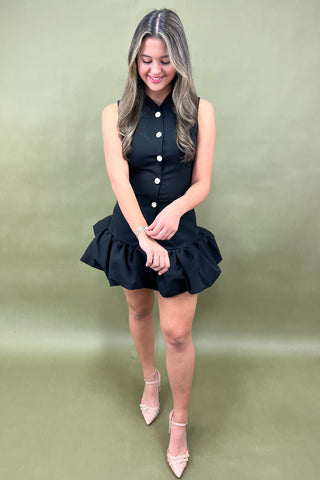 Woman wearing a black dress with white buttons on a green background