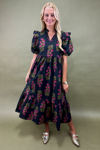 Woman wearing a dark floral dress against a plain background