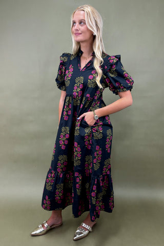 Woman wearing a dark floral dress against a plain background